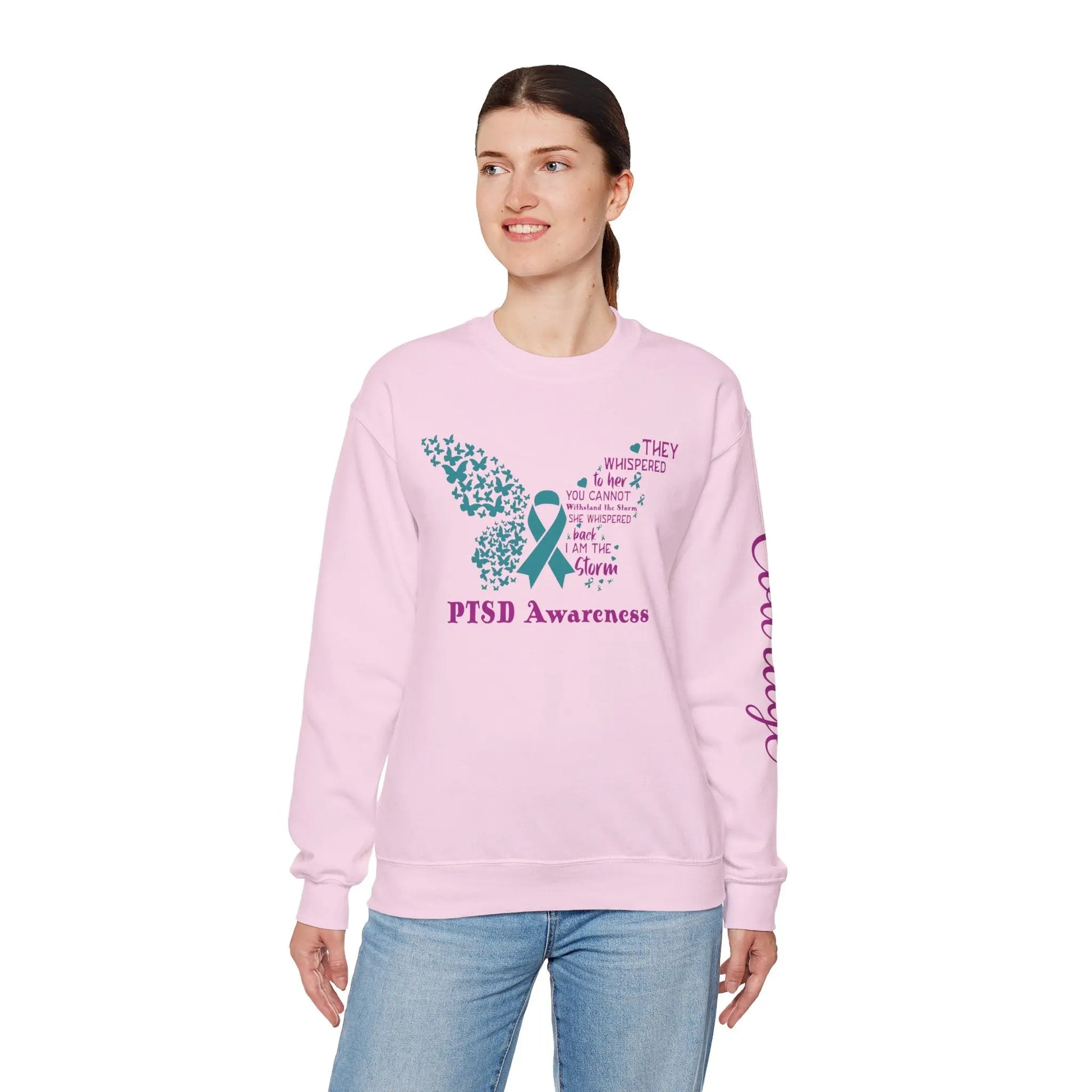 Lady wearing, She Is The Storm PTSD Awareness sweatshirt with butterfly design and 'Courage' print on the left arm. Empowering women’s empowerment tee.