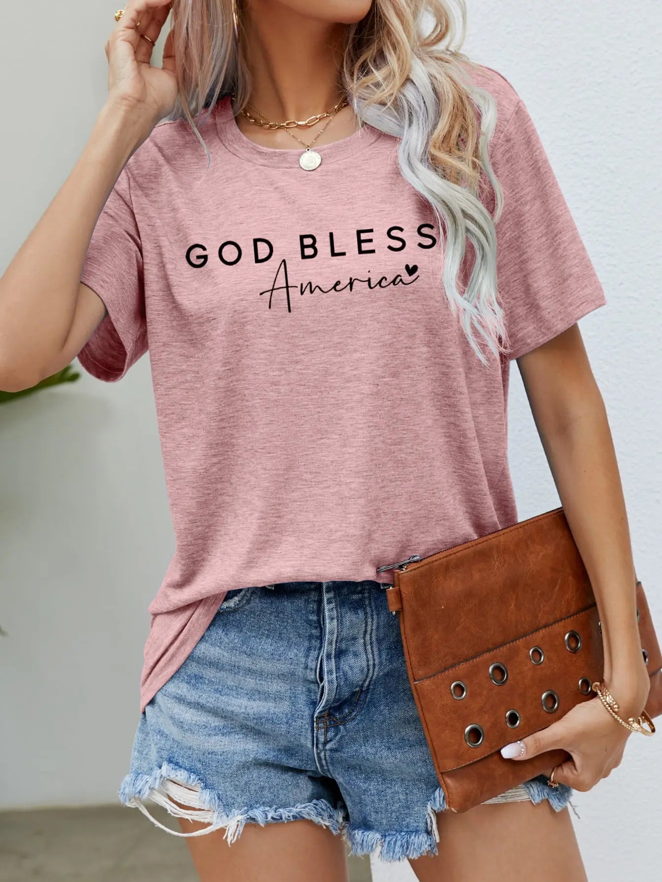 Blush Pink God Bless America Graphic Short Sleeve Tee with bold patriotic design, breathable fabric, and a comfortable fit for stylish everyday wear.