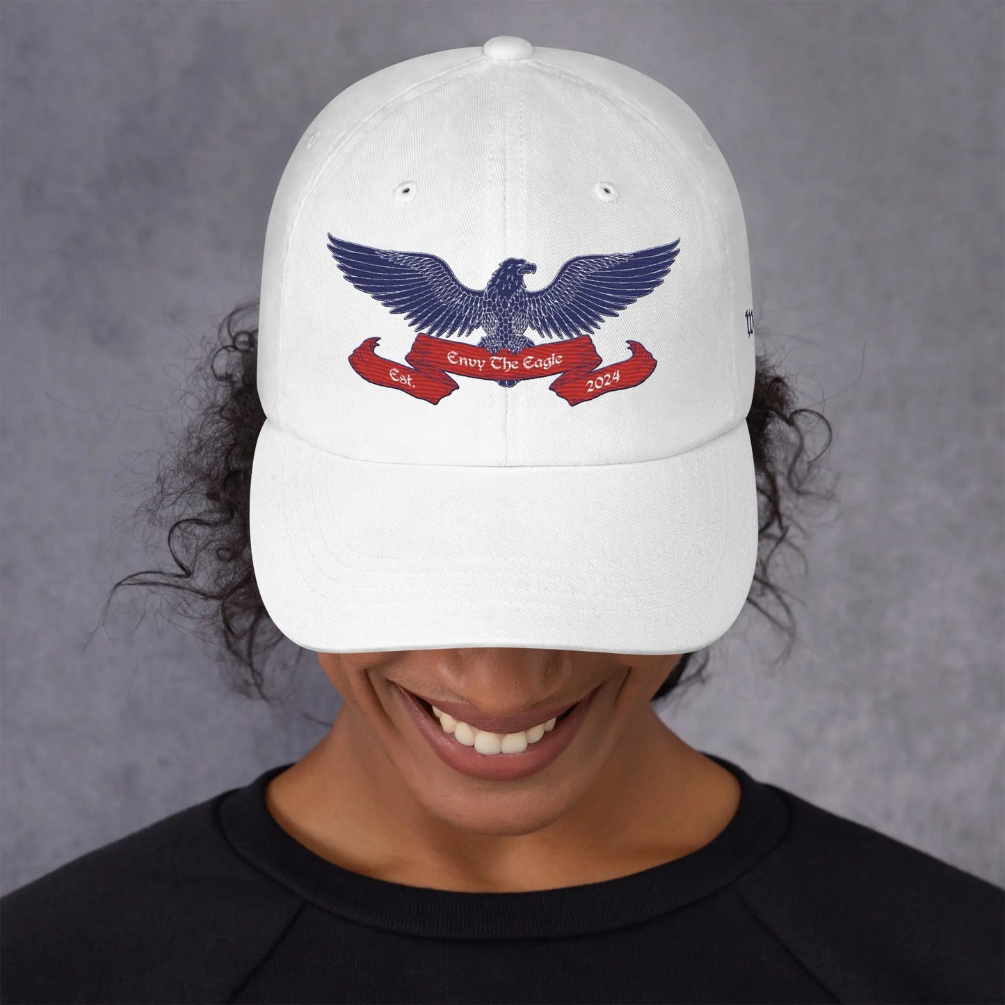 Woman wearing White embroidered baseball cap text We The People on left side Envy The Eagle™ Logo embroidered on front. Patriotism Love for Country